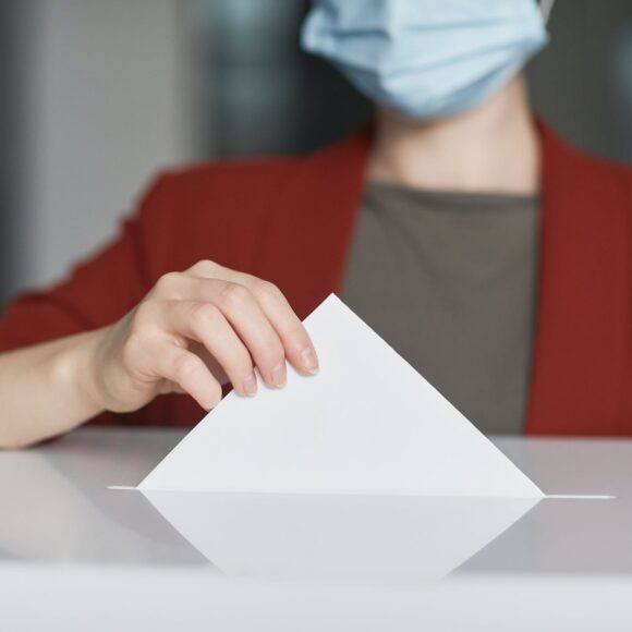 ballot box with person casting a vote