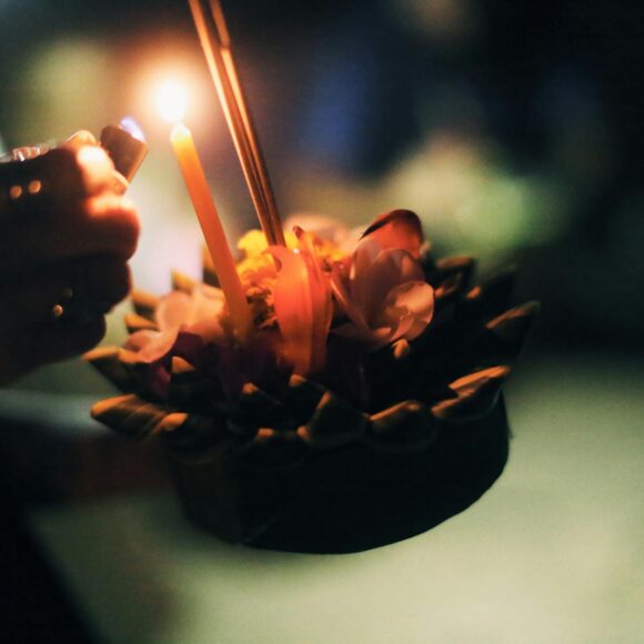 crop person burning candle on krathong