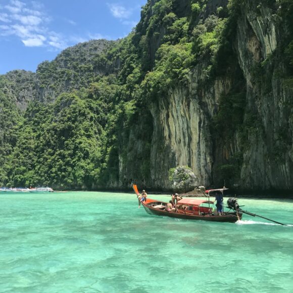 small boat in body of water near a cliff