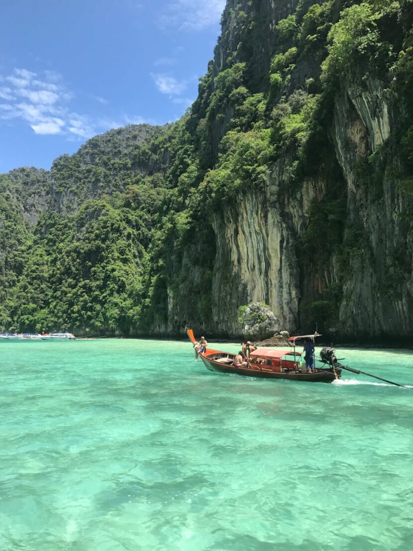 Small Boat in Body of Water Near a Cliff