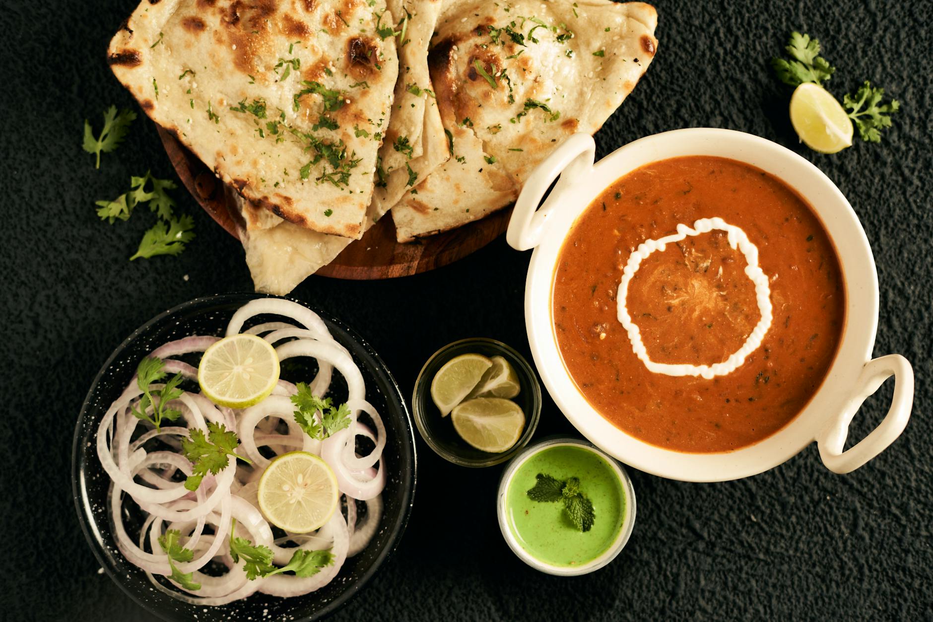 top view of an indian dish with onions and flatbread on the side