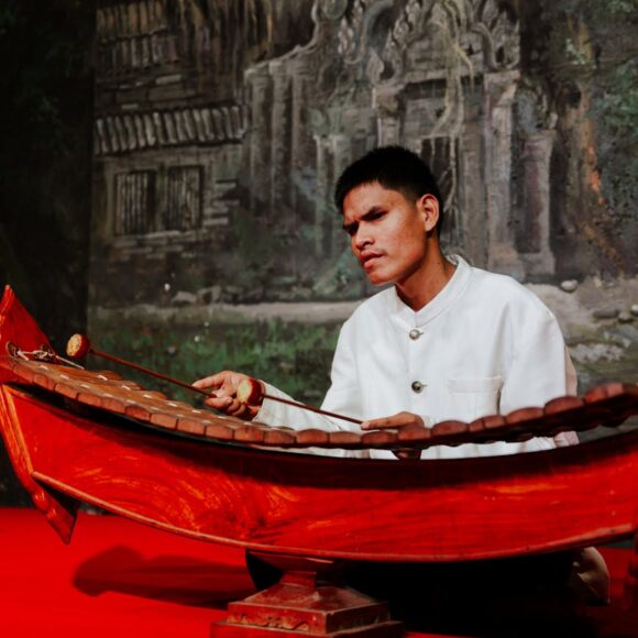 man sitting and playing traditional musical instrument