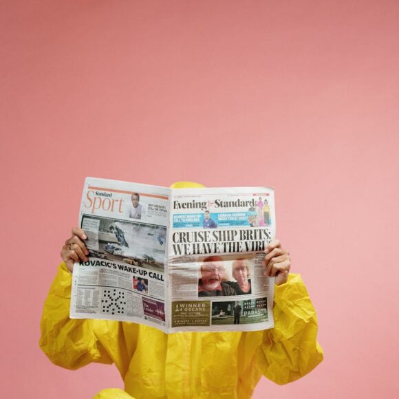 person in yellow coveralls reading newspaper