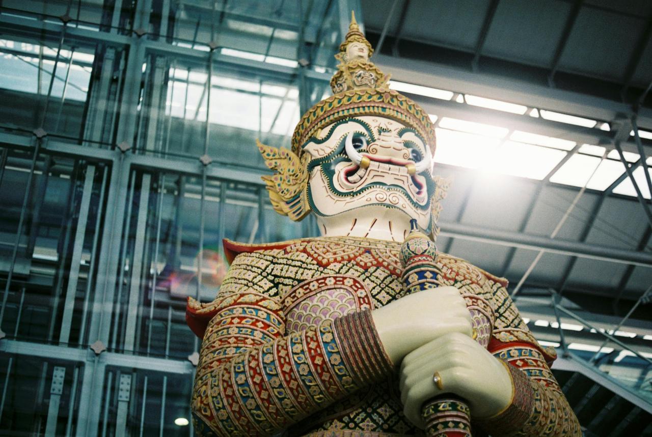 Thai ariline change01 可愛曼谷 narak Club Colorful Guardian Demon Statue Indoors Hands Folded Around a Staff with an Ornate Headdress and Patterned Armor
